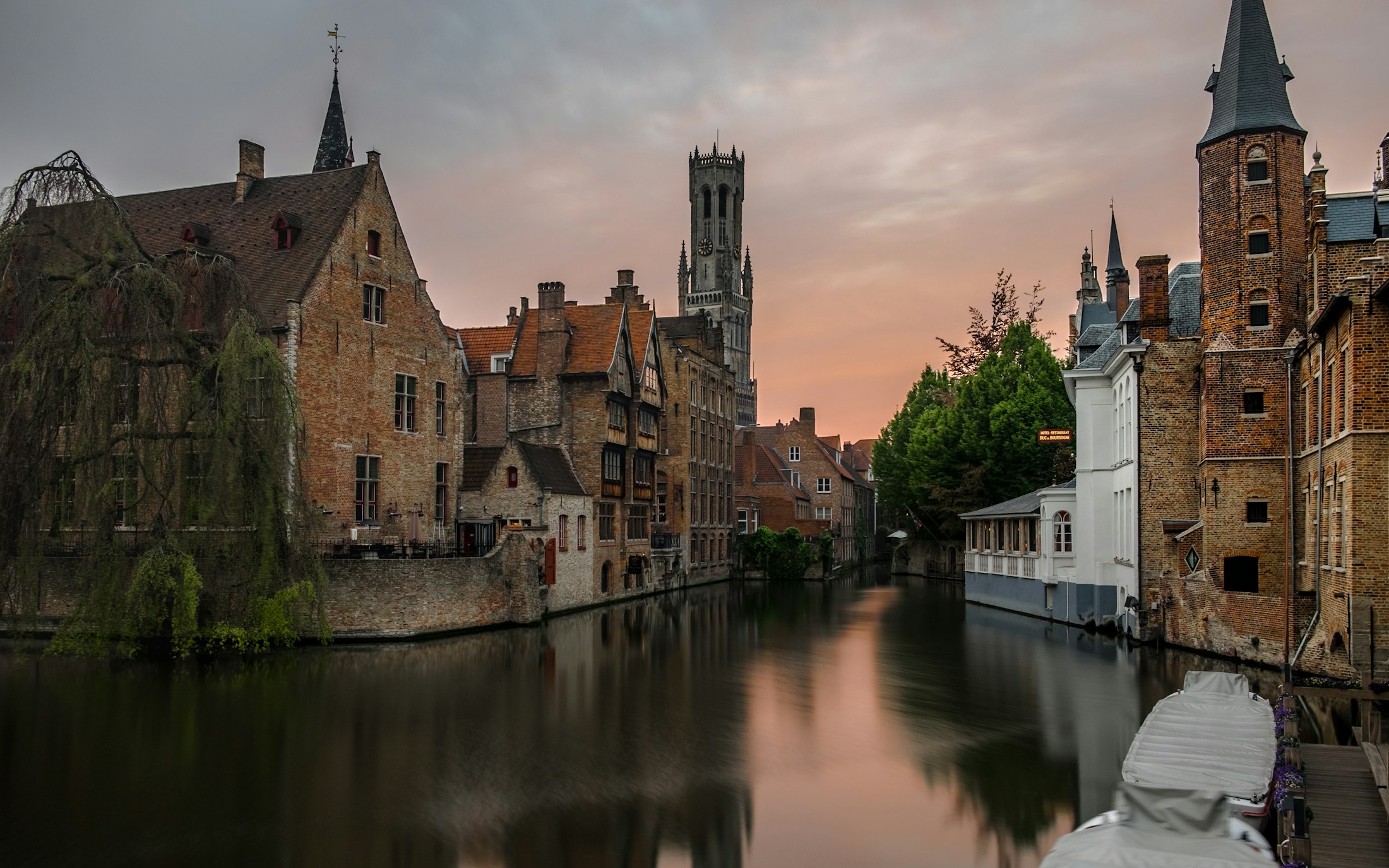 Bruges Belfry and historic houses beside the canal at sunset